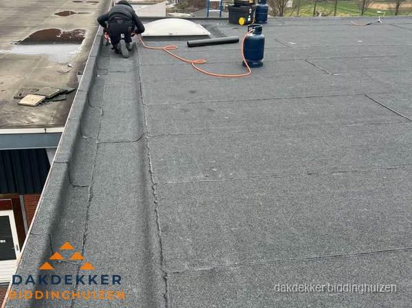 Dakdekker repareert bitumen dakbedekking op groot plat dak in Biddinghuizen Dakdekker repareert bitumen dakbedekking op groot plat dak in Biddinghuizen